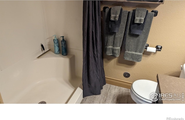 full bathroom with wood finished floors, toilet, and a shower with curtain