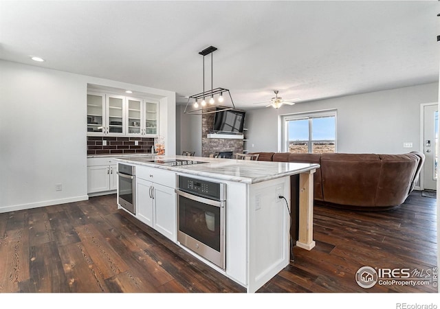 kitchen with open floor plan, a kitchen island with sink, and stainless steel oven