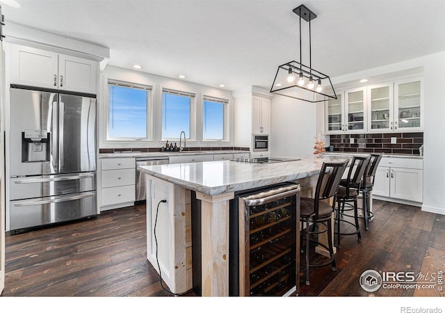 kitchen featuring stainless steel appliances, tasteful backsplash, a kitchen island, a sink, and beverage cooler