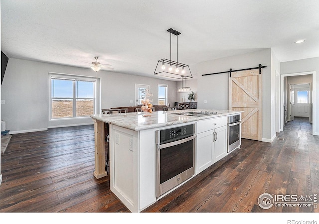 kitchen featuring open floor plan, a barn door, oven, and white cabinetry