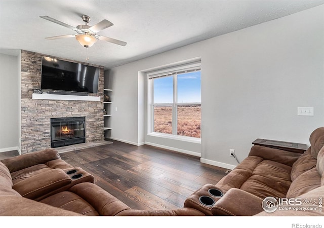 living room with a textured ceiling, ceiling fan, a fireplace, baseboards, and wood-type flooring