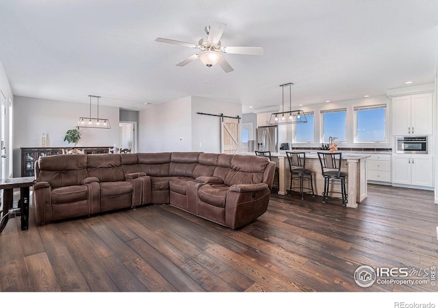 living area featuring ceiling fan, a barn door, dark wood-style flooring, and recessed lighting