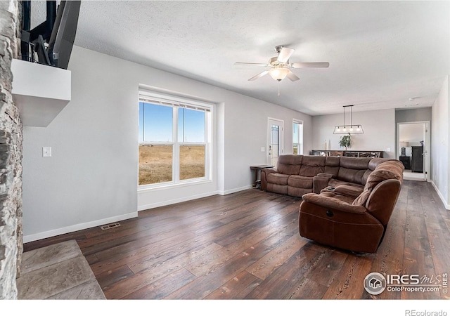 living room featuring hardwood / wood-style flooring, ceiling fan, baseboards, and a textured ceiling