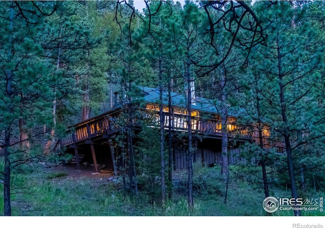 back of house with a deck and a view of trees