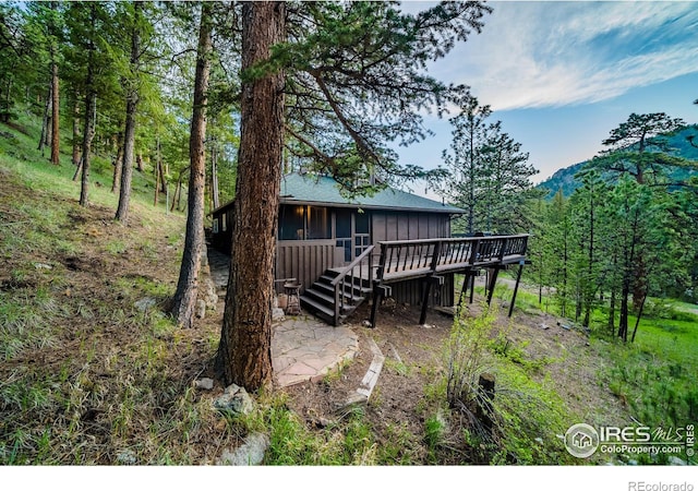 exterior space with stairway, a patio, a deck, and a view of trees