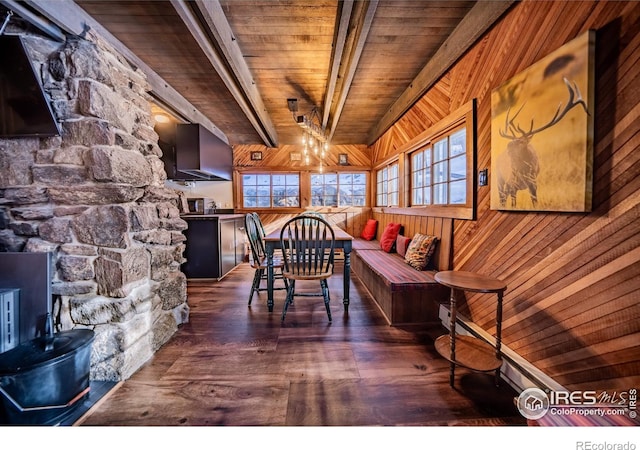 dining room featuring wood walls, wooden ceiling, wood finished floors, and beam ceiling