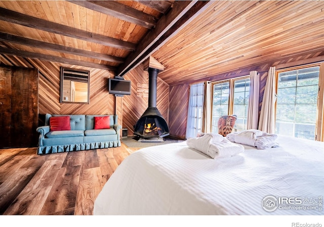 bedroom featuring a wood stove, wood walls, wood finished floors, wooden ceiling, and beamed ceiling