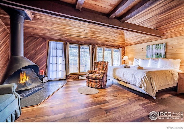 bedroom featuring wood ceiling, wood finished floors, a wood stove, wood walls, and beam ceiling