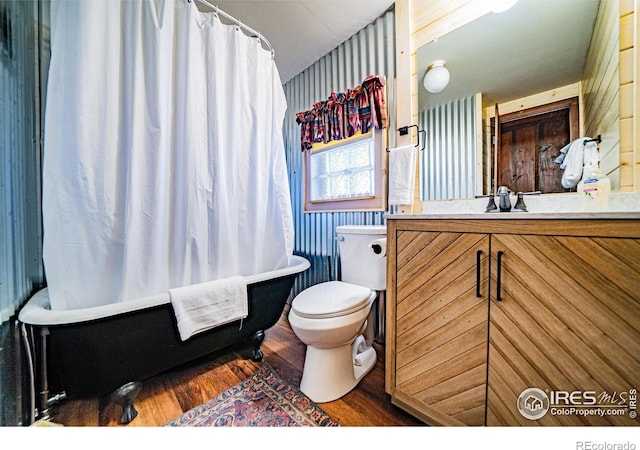 full bath featuring toilet, a washtub, a shower with shower curtain, wood finished floors, and vanity