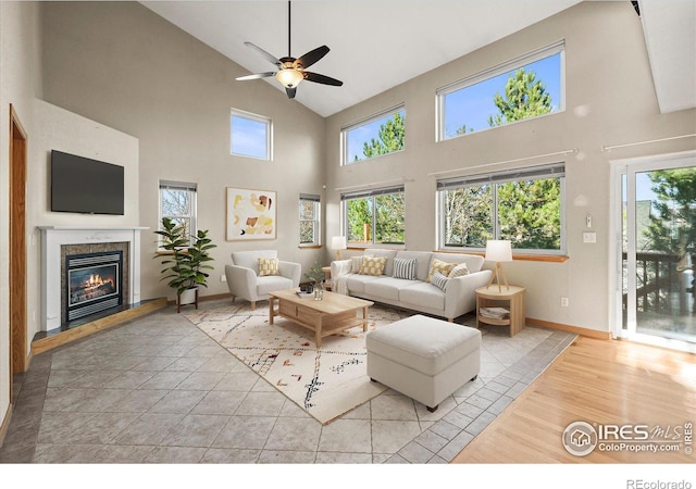 living room featuring ceiling fan, a fireplace, baseboards, and a wealth of natural light