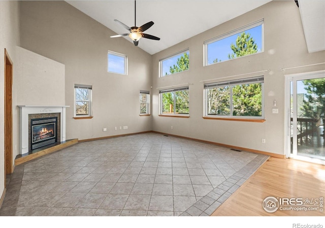 unfurnished living room featuring light tile patterned floors, a premium fireplace, a wealth of natural light, and baseboards