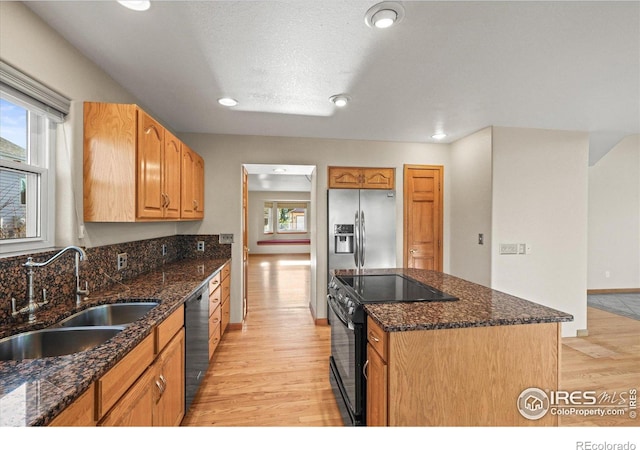 kitchen with dishwashing machine, light wood-style flooring, black electric range, stainless steel refrigerator with ice dispenser, and a sink