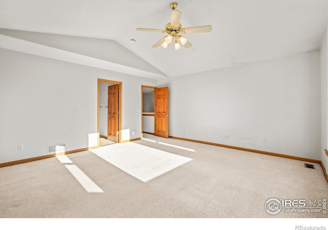 spare room with lofted ceiling, visible vents, and light carpet