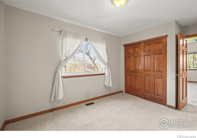 unfurnished bedroom with baseboards, a closet, visible vents, and carpet flooring