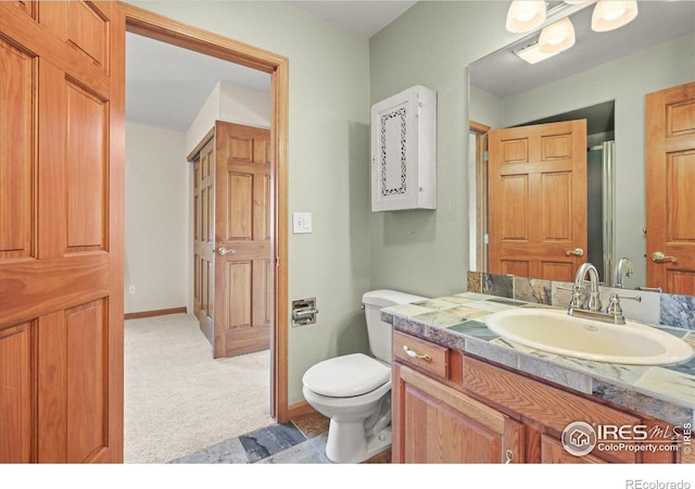 bathroom featuring vanity, toilet, and baseboards