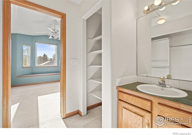 bathroom with vaulted ceiling, ceiling fan, vanity, and baseboards