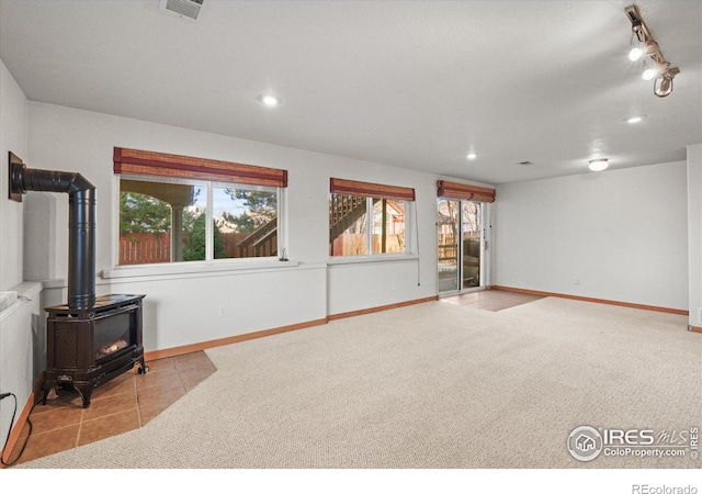 carpeted living area with recessed lighting, tile patterned floors, a wood stove, and baseboards