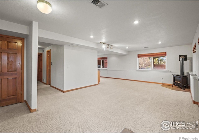 below grade area with recessed lighting, carpet floors, visible vents, baseboards, and a wood stove