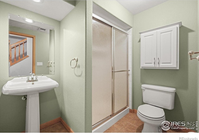 bathroom featuring baseboards, a shower stall, toilet, and tile patterned floors