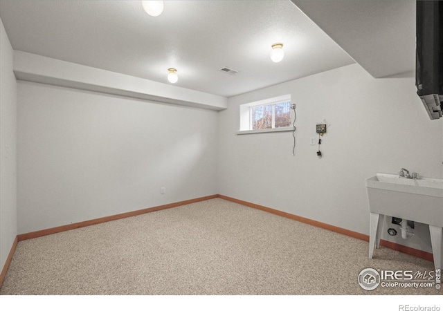 basement featuring carpet floors, visible vents, and baseboards