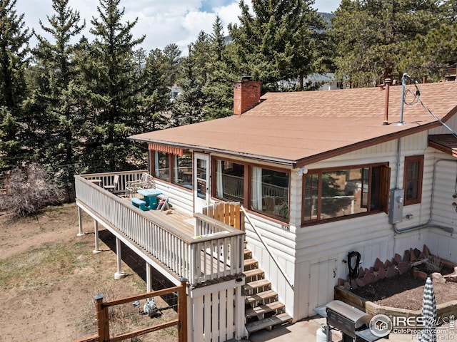 view of front of property featuring a chimney, a wooden deck, and stairs