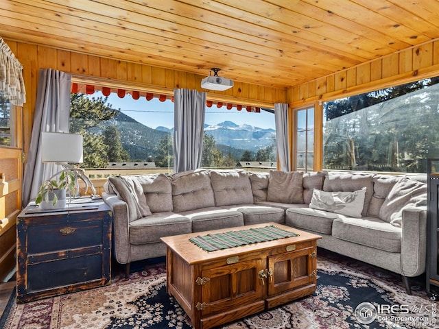 living room featuring a healthy amount of sunlight, wooden ceiling, wooden walls, and a mountain view