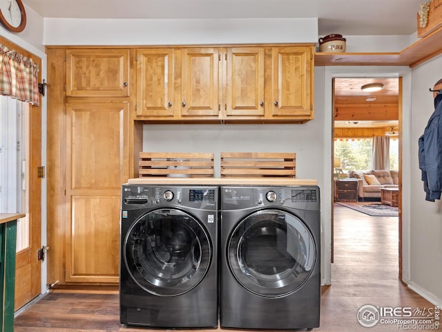 clothes washing area with washing machine and dryer, dark wood-style flooring, and cabinet space