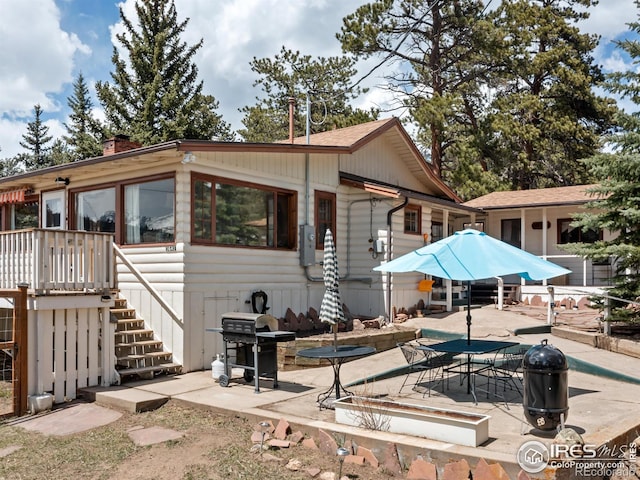 back of house featuring stairs, a chimney, and a patio area