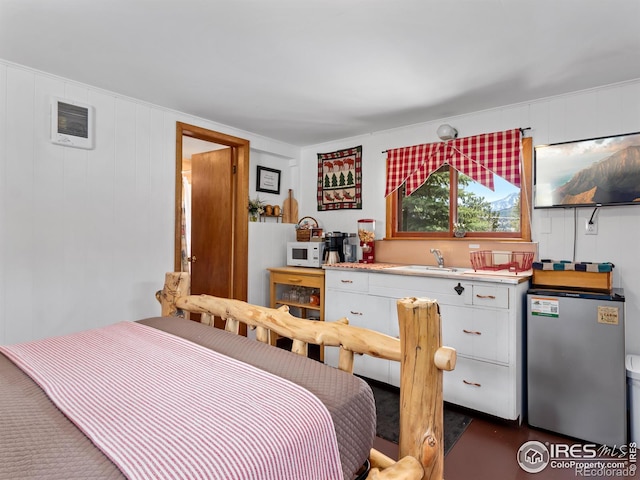 bedroom featuring freestanding refrigerator, visible vents, and a sink