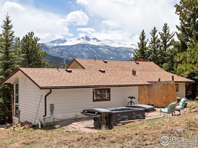 rear view of property with roof with shingles, a chimney, and a mountain view