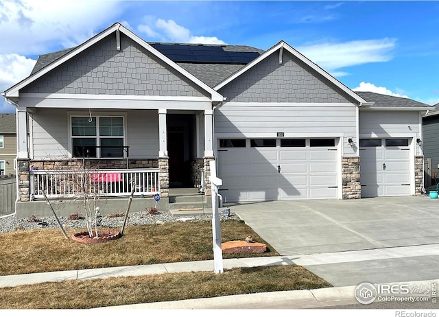 craftsman inspired home with a garage, covered porch, driveway, and stone siding