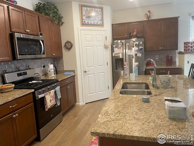 1431 Vantage Pkwy, Berthoud, CO 80513 - kitchen with appliances with stainless steel finishes, a sink, backsplash, light wood-style flooring, and light stone countertops