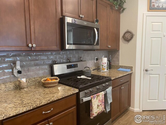 1431 Vantage Pkwy, Berthoud, CO 80513 - kitchen featuring stainless steel appliances, backsplash, light stone countertops, and light wood-style floors