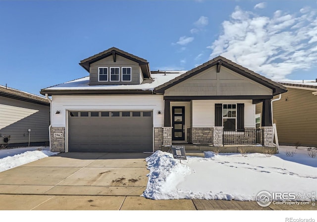 craftsman house with covered porch, concrete driveway, stone siding, and an attached garage