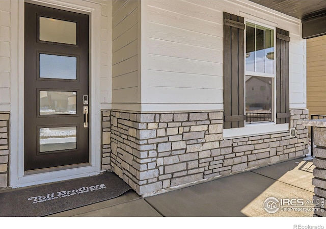 view of exterior entry with covered porch and stone siding