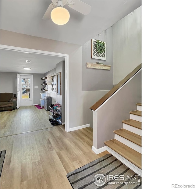 staircase with wood finished floors, a ceiling fan, and baseboards