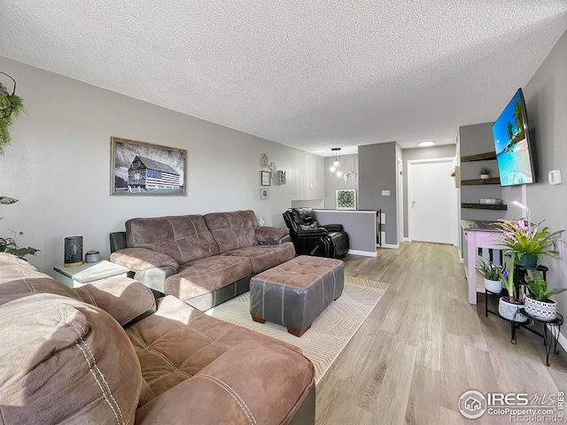 living room featuring baseboards, a textured ceiling, and light wood finished floors