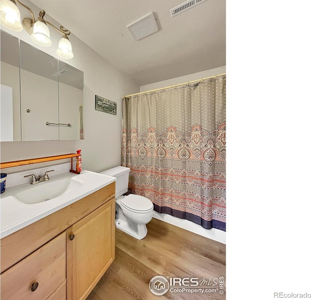 bathroom with visible vents, vanity, toilet, and wood finished floors