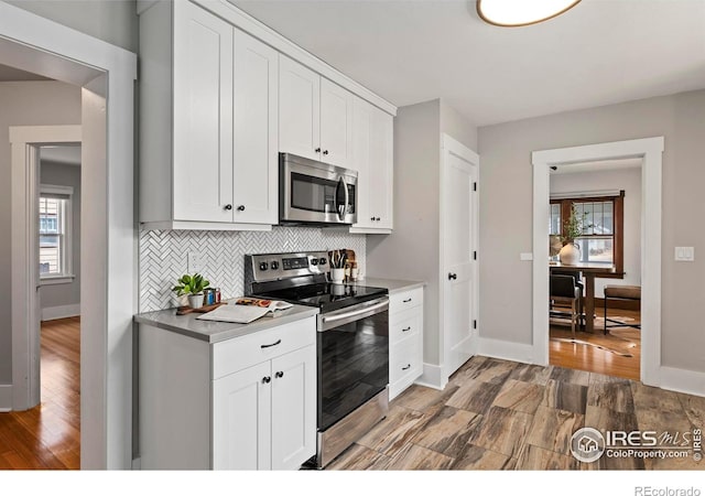 530 Laporte Ave, Fort Collins, CO 80521 - kitchen with light countertops, white cabinetry, backsplash, light wood-style floors, and appliances with stainless steel finishes