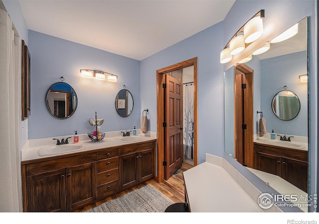 full bath featuring double vanity, a sink, and wood finished floors