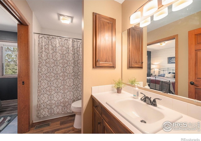 bathroom with toilet, a shower with shower curtain, wood finished floors, visible vents, and vanity