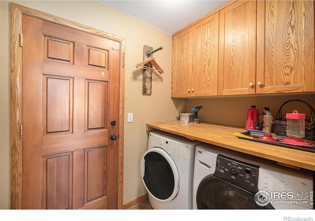 clothes washing area featuring cabinet space, independent washer and dryer, and baseboards