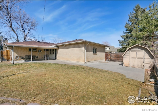 rear view of house featuring a patio, an outbuilding, fence, a yard, and a shed