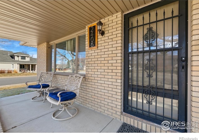 property entrance featuring covered porch and brick siding