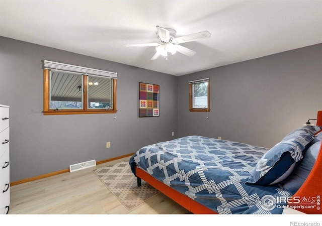 bedroom featuring light wood finished floors, baseboards, visible vents, and a ceiling fan