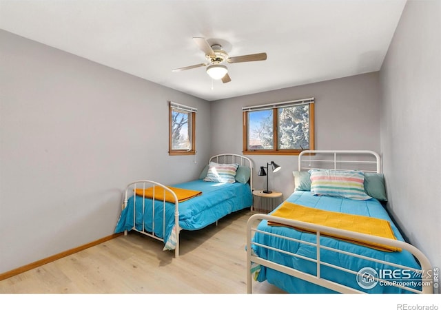 bedroom with ceiling fan, wood finished floors, and baseboards