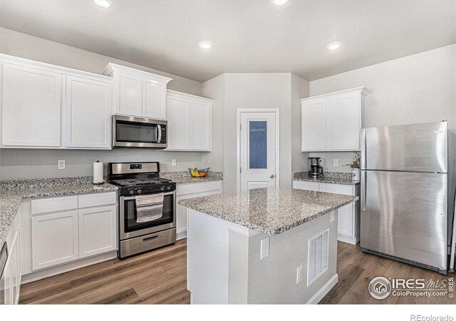 2539 Alto St, Fort Lupton, CO 80621 - kitchen featuring white cabinetry, appliances with stainless steel finishes, light stone counters, and wood finished floors