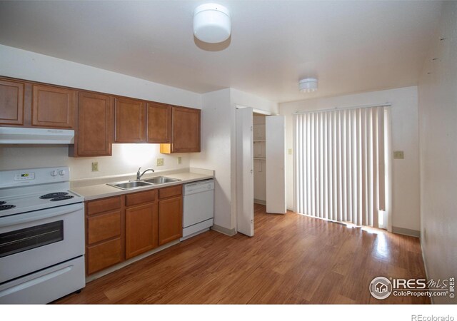 216-218 E Saint Clair Ave, Longmont, CO 80504 - kitchen featuring under cabinet range hood, white appliances, a sink, light wood-style floors, and brown cabinets