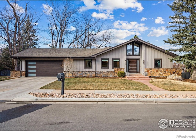 mid-century modern home with stone siding, a front yard, concrete driveway, and an attached garage