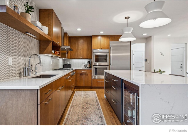 kitchen featuring open shelves, stainless steel appliances, hanging light fixtures, a sink, and beverage cooler